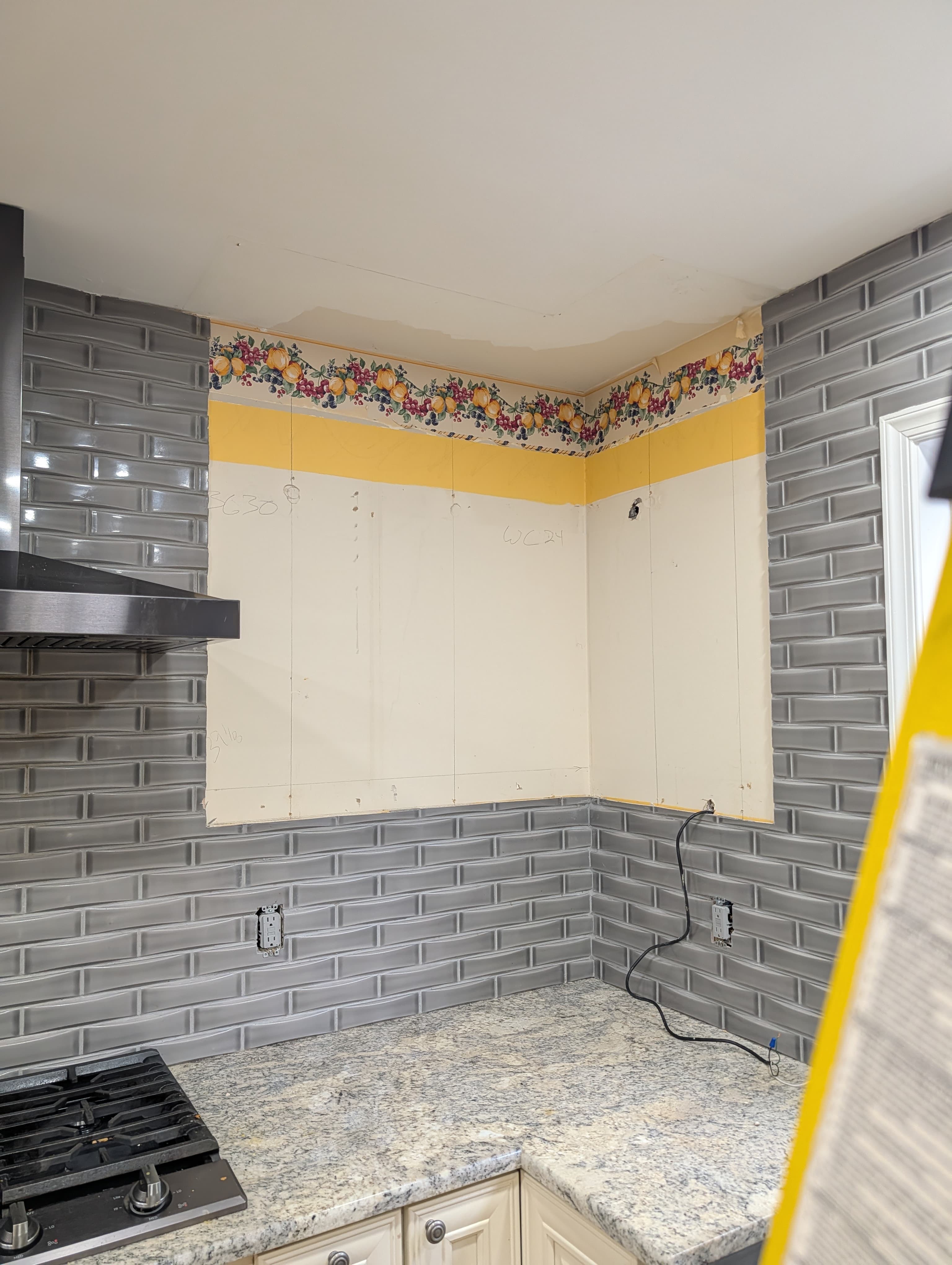 Original Herndon kitchen wall during demo, corner view with old wallpaper border and patched drywall